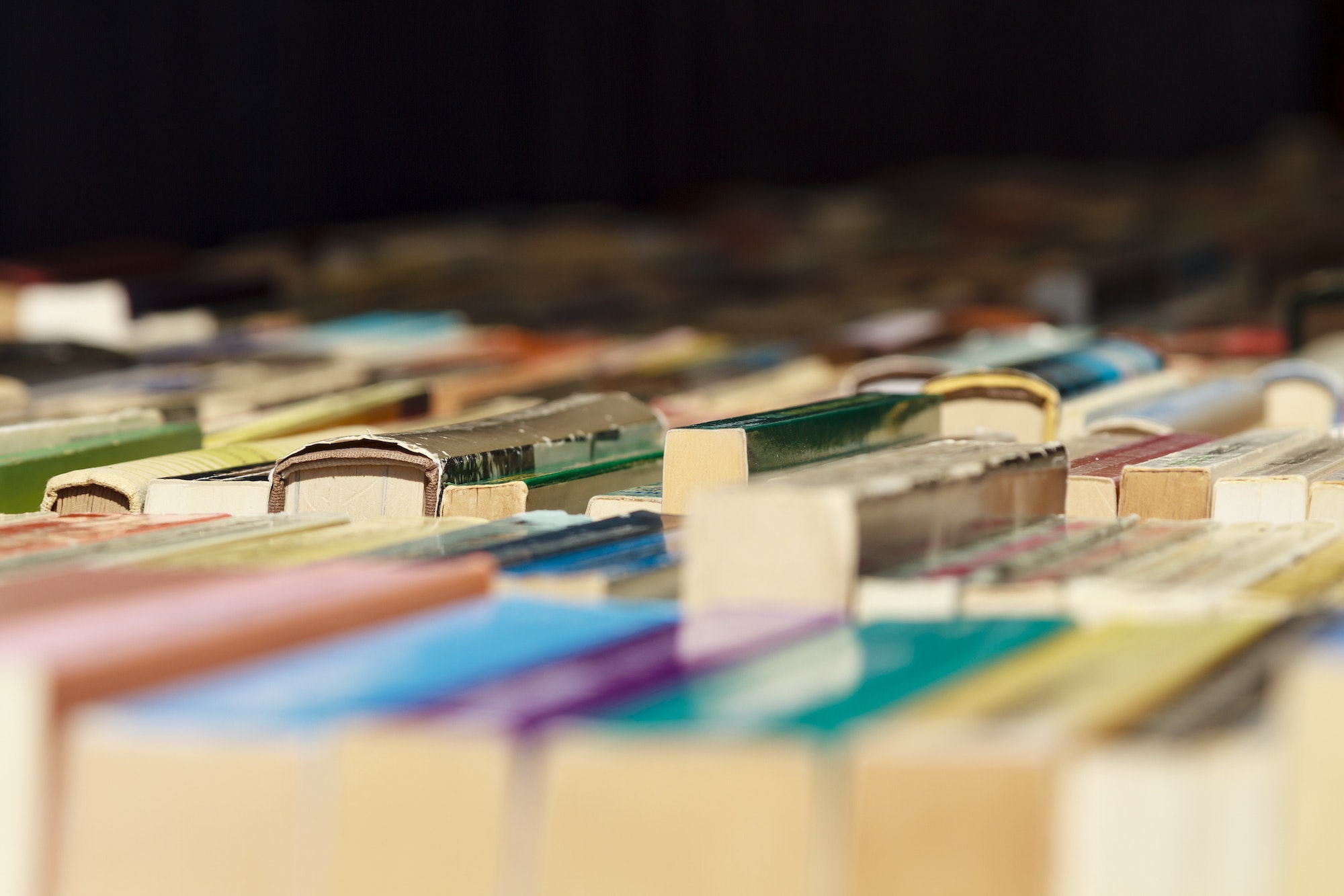 Used second hand books for sale on a book market stall in perspective bright colors on a table.